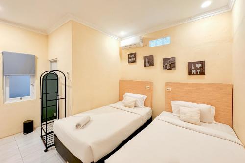 a bedroom with two beds and a window at Perdana Kasih Hotel Pemuda Klaten Mitra RedDoorz in Solo