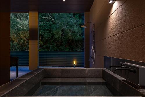 a bathroom with a large window and a stone staircase at EZRA VILLA shirahama in Shirahama