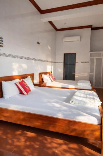 a bedroom with two beds with white sheets and red pillows at Vườn Dừa Cam Bình 2 in Vĩnh Thạnh