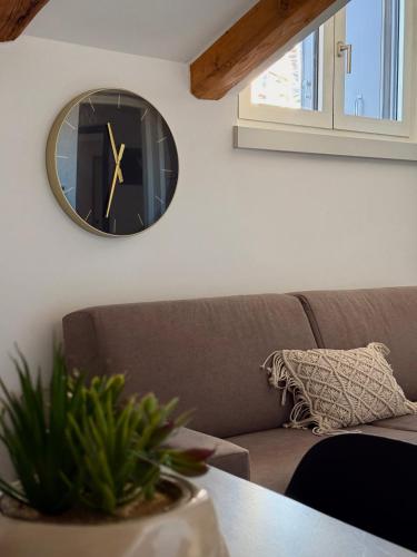 a clock hanging on a wall next to a couch at CELLINI HOME in Trieste