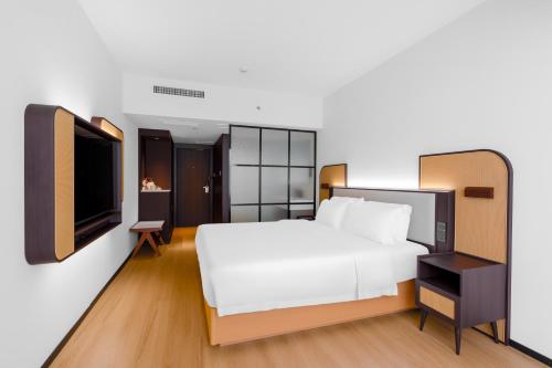 深セン市にあるシャンスイ トレンズ ホテル ファーチャンペーの白いベッドと薄型テレビが備わるホテルルームです。