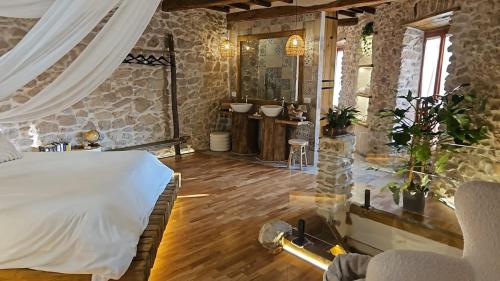 een slaapkamer met een bed en een stenen muur bij La Nuit d'Amélie 2 in Norma