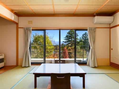 a room with a table and a large window at Suzuranso in Komagane
