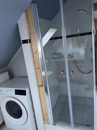 a bathroom with a shower and a washing machine at NEU! Ferienwohnung Bottelterberg in Saarburg