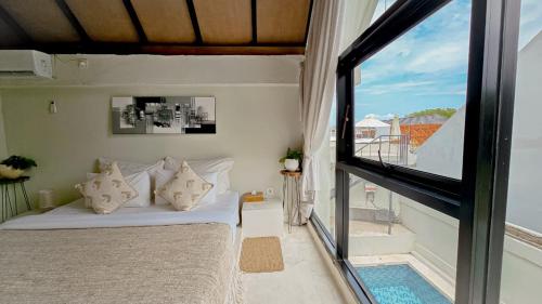een slaapkamer met een bed en een groot raam bij KAYA Uluwatu in Uluwatu