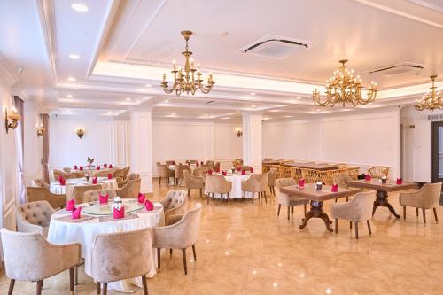 a dining room with tables and chairs and chandeliers at Le Haute Hotel Hai Phong in Hai Phong