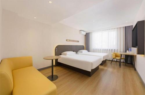 a hotel room with a bed and a yellow chair at Jinjiang Inn - Xishan Road in Dalian