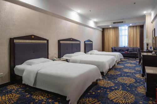 una fila de camas en una habitación de hotel en Zhongshan Hui Quan Hotel, en Zhongshan