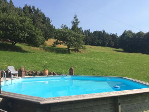 a swimming pool in a yard with a field and trees at Les Fermes De Pinpin in Labaroche