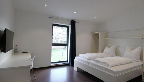 a white bedroom with a bed and a window at Neumann's Übernachtung in Plankstadt