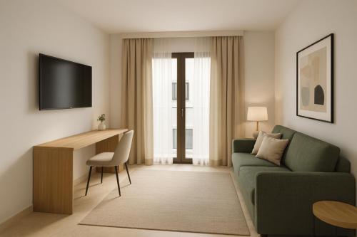 een woonkamer met een groene bank en een bureau bij Hotel Boutique Petit París in Port de Pollença
