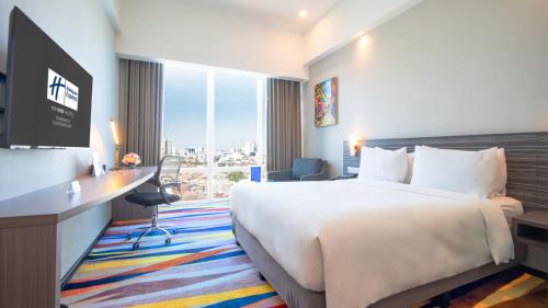 Una habitación de hotel con una cama, un escritorio y un televisor. en Holiday Inn Express Surabaya CenterPoint by IHG, en Surabaya