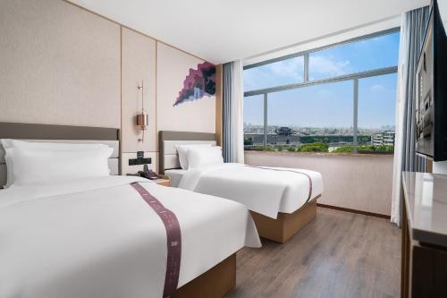 deux lits dans une chambre d'hôtel avec une fenêtre dans l'établissement eLong Hotel Suzhou Guanqian Street, à Suzhou