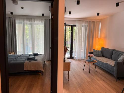 een slaapkamer en een woonkamer met een bed en een bank bij Sea&Forest Międzyzdroje Amber Suite in Międzyzdroje