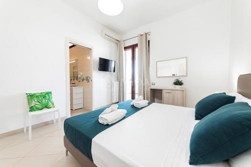 a white bedroom with a large bed with blue pillows at Mama Bed in Porto Cesareo