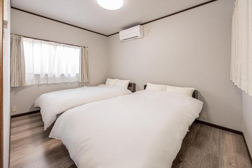 two beds in a white room with a window at 富士飛鳥 in Fujiyoshida