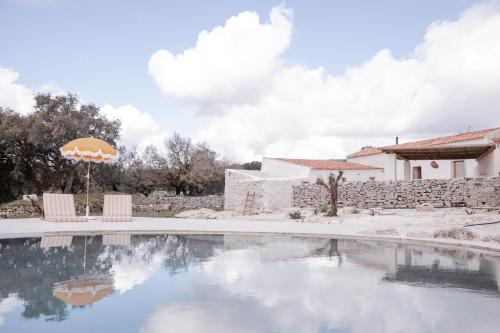 een zwembad met een parasol en een huis bij Casa d'Aire in Porto de Mós