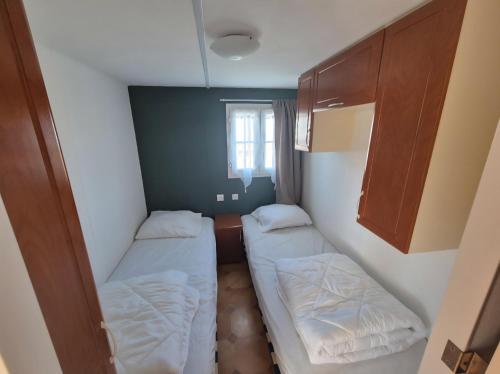 ein kleines Zimmer mit zwei Betten und einem Fenster in der Unterkunft Mobil-home camping Le Ptit Rio in Noyelles-sur-Mer