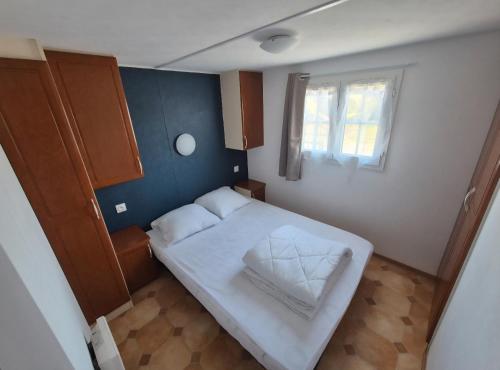 une petite chambre avec un lit blanc et une fenêtre dans l'établissement Mobil-home camping Le Ptit Rio, à Noyelles-sur-Mer