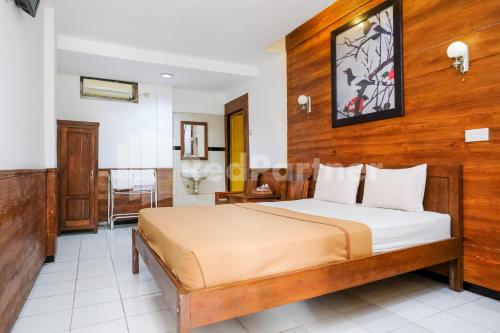 a bedroom with a bed with a wooden wall at The Soemarsono Hotel near Ambarrukmo Plaza Mall RedPartner in Yogyakarta
