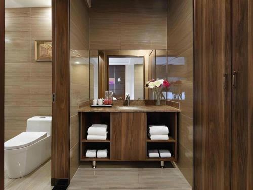 ein Badezimmer mit Waschbecken, Toilette und Spiegel in der Unterkunft Hanyong Hotel Shenzhen International Exhibition Center in Fenghuangwei