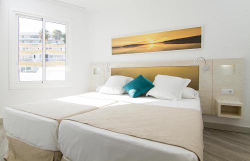 2 camas en una habitación blanca con 2 almohadas azules en Checkin Bungalows Atlántida, en Los Cristianos