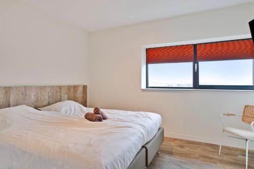 a teddy bear laying on a bed in a bedroom at Vacation apartment Veerse Muze in Kamperland