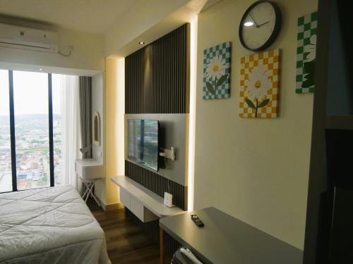 バタム・センターにあるPollux Habibie Apartment Batamのベッドルーム1室(ベッド1台、壁掛け時計付)