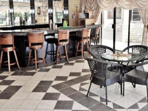 a bar with a checkered floor and tables and chairs at Lakefield Hotel in Benoni