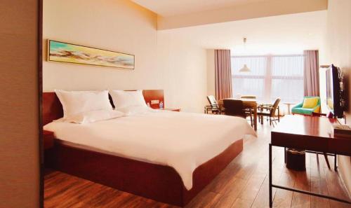 a hotel room with a large bed and a dining room at Hangzhou Berman Hotel in Hangzhou