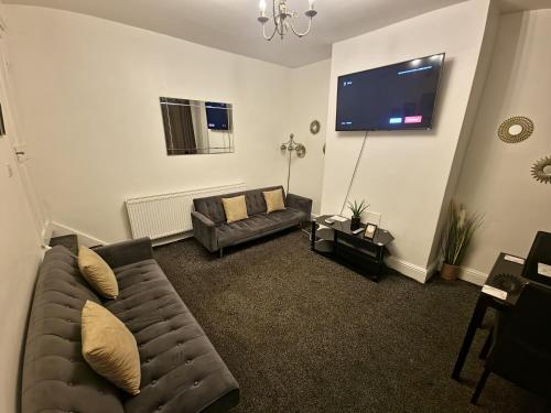 a living room with a couch and a flat screen tv at Modern Cosy 2 Bed Room Home In Leeds - 1 min from St James Hospital and 6 mins to Leeds City Centre, Free Parking, Wi-Fi in Central Station