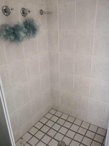 a bathroom with a shower with white tile at Duplex in Tableview in Cape Town