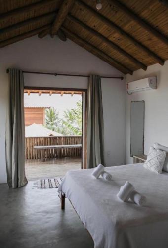 a bedroom with a bed and a large window at Canto do Mar Caraiva in Caraíva