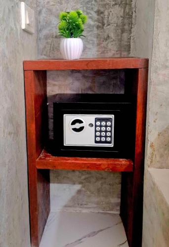a microwave on a wooden shelf with a potted plant at Lanta Valom buri in Ko Lanta