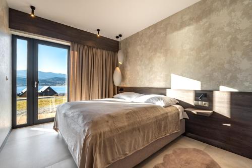 a bedroom with a large bed and a large window at Apartament Lake&Hill View w Karkonoszach z możliwym dostępem do strefy WELLNESS w kompleksie in Sosnówka