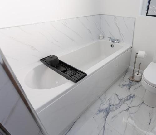 a remote control sitting on a white bath tub in a bathroom at The Views Retreat in Newcastle