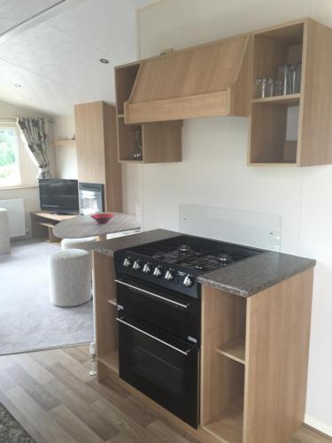 a kitchen with a stove top oven in a room at Lovely 3 Bed Caravan, Milford on Sea in Milford on Sea