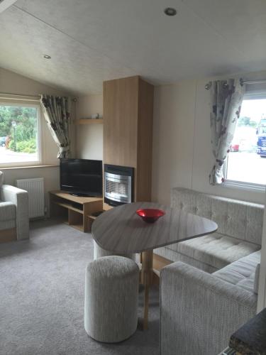 uma sala de estar com uma mesa e um sofá em Lovely 3 Bed Caravan, Milford on Sea em Milford on Sea
