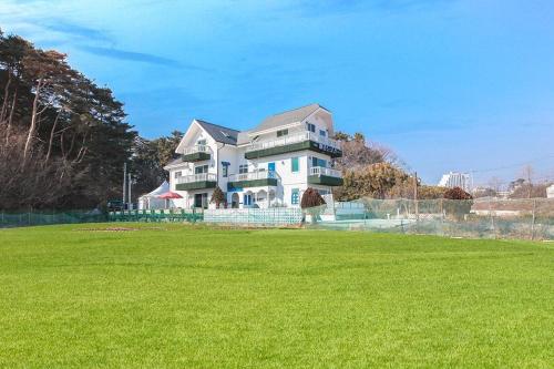 ein großes Haus mit einem grünen Feld davor in der Unterkunft Gangneung Maison de Rose in Gangneung