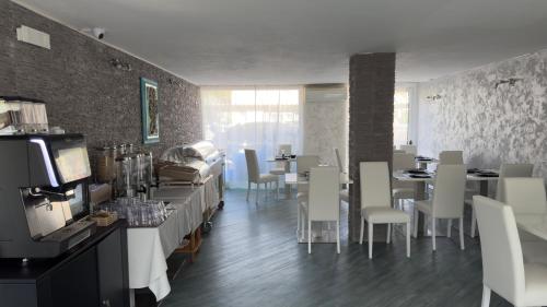 Un comedor con sillas y mesas blancas y una habitación con una involuntaria en Hotel Al Sole, en Grado