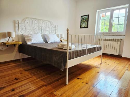 a bedroom with a white bed with a wooden floor at Casa de Emaús - Gerês in Terras de Bouro