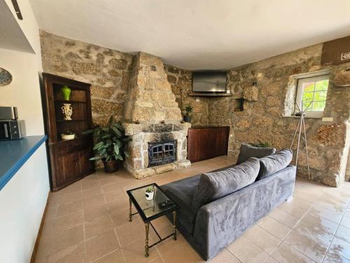 a living room with a couch and a stone fireplace at Casa de Emaús - Gerês in Terras de Bouro