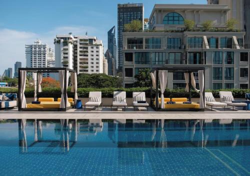 a pool with lounge chairs next to a building at TRIBE Living Bangkok Sukhumvit 39 by AccorHotels in Bangkok