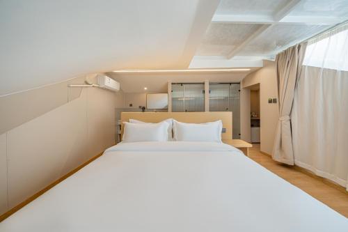 a bedroom with a large white bed and a window at MEI DI DU JIA HOTEL in Shanghai