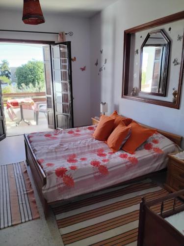 1 dormitorio con 1 cama con almohadas de color naranja y espejo en Résidence Kyranis appartement Gyptis, en Sfax