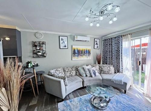 ein Wohnzimmer mit einer Couch und einem Glastisch in der Unterkunft Buenos Manor in Roodepoort