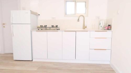 una cucina bianca con lavello e frigorifero di הצימר של תמר - אורחן מתאים לדתיים a Safed