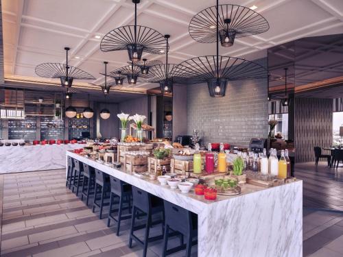 ジャカルタにあるメルキュール ジャカルタ パンタイ インダ カプックのテーブルと椅子が備わるレストランでのビュッフェ