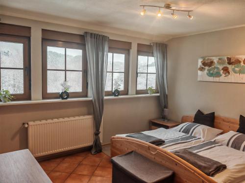 a bedroom with a bed and two windows at Landhaus am Brubbel in Wallenborn