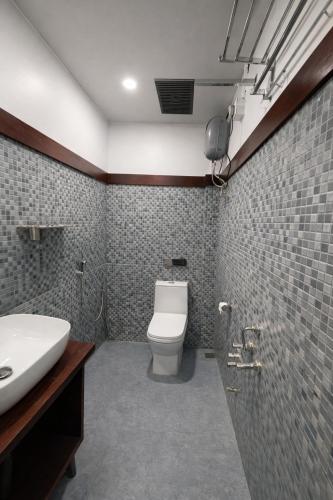 a bathroom with a white toilet and a sink at Landmark Inn in Lanka